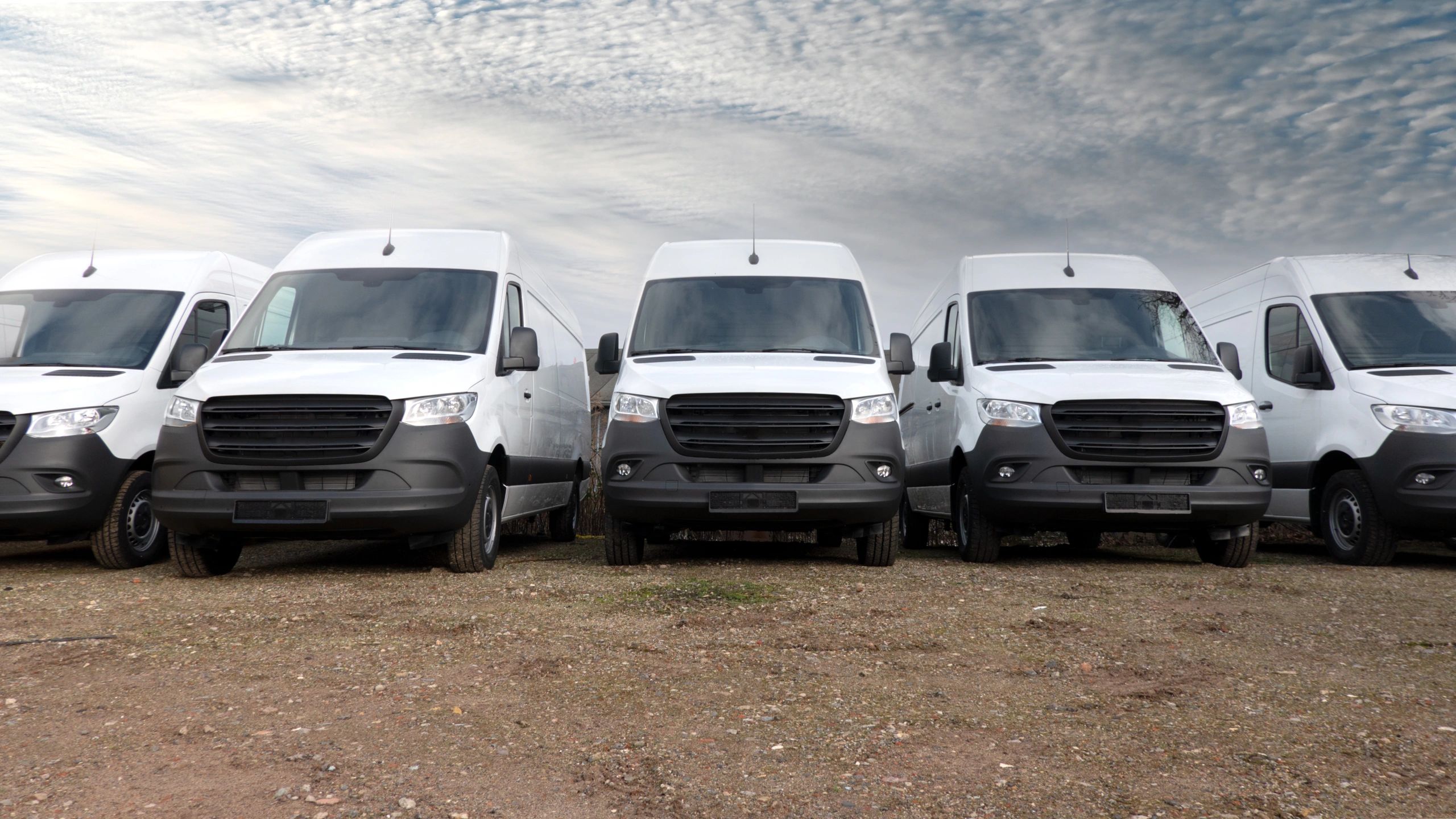 Fleet of white delivery vans parked in a row